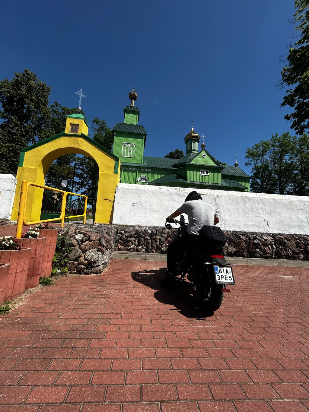 Motocyklista przed drewnianą podlaską cerkwią